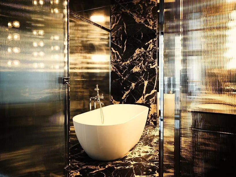 a bathtub sits within a frosted-glass cube inside one of the rooms