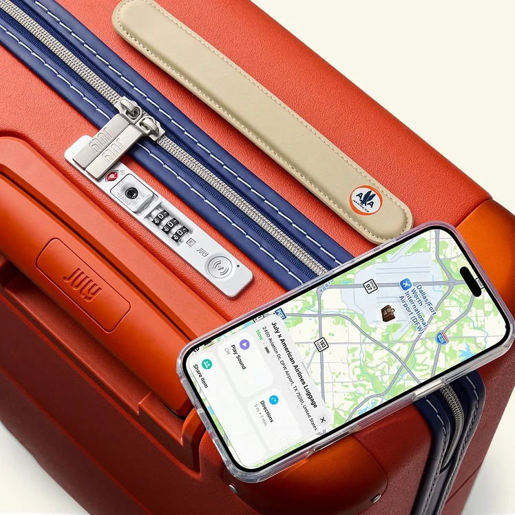 The collection's CaseSafe lock beside a phone displaying luggage tracking. Official product demonstration image: July.